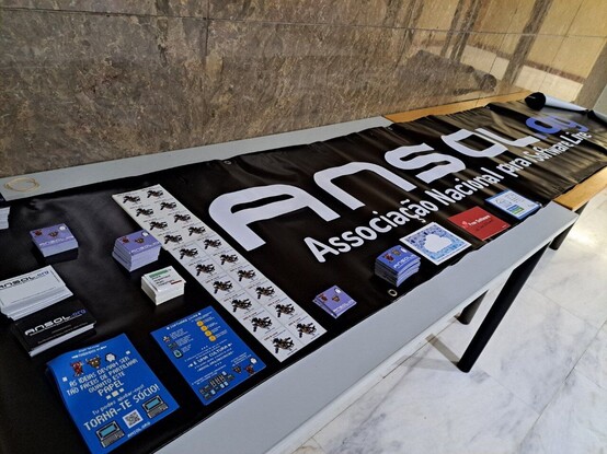 A table with a banner saying ANSOL and several stickers related with Free Software