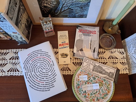 Two books, a green candle, a rounded tin with small pieces of paper and some bookmarks over a table