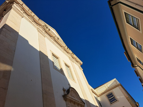A photo taken from below showing the top of some old buildings against a blue and clear sky