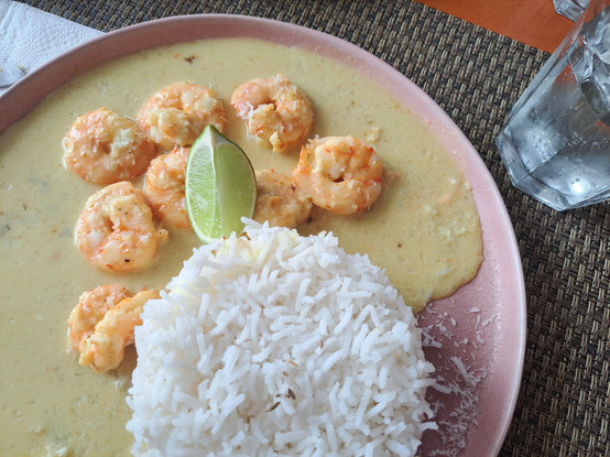 A plate with rice and shrimps with a curry sauce and a quarter of a lime in the restaurant Cardamomo located in Leiria, Portugal