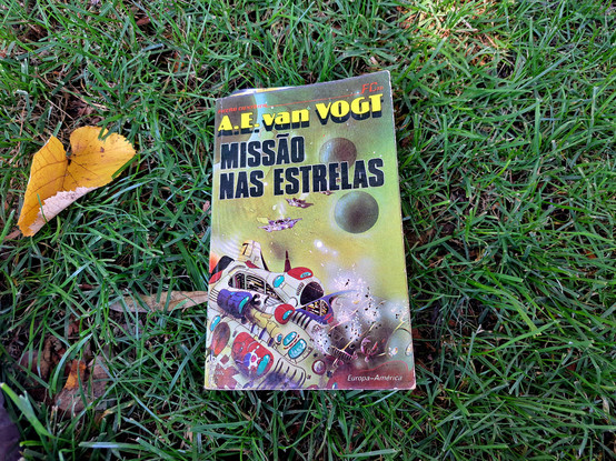 The book Mission to the stars by van Vogt, in a Portuguese edition, over grass in a park