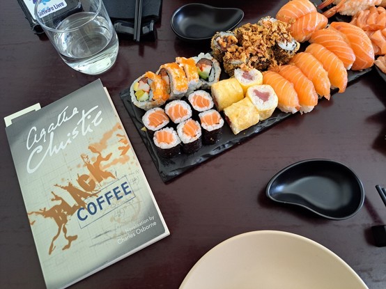 The book Black Coffee next to a dish of sushi