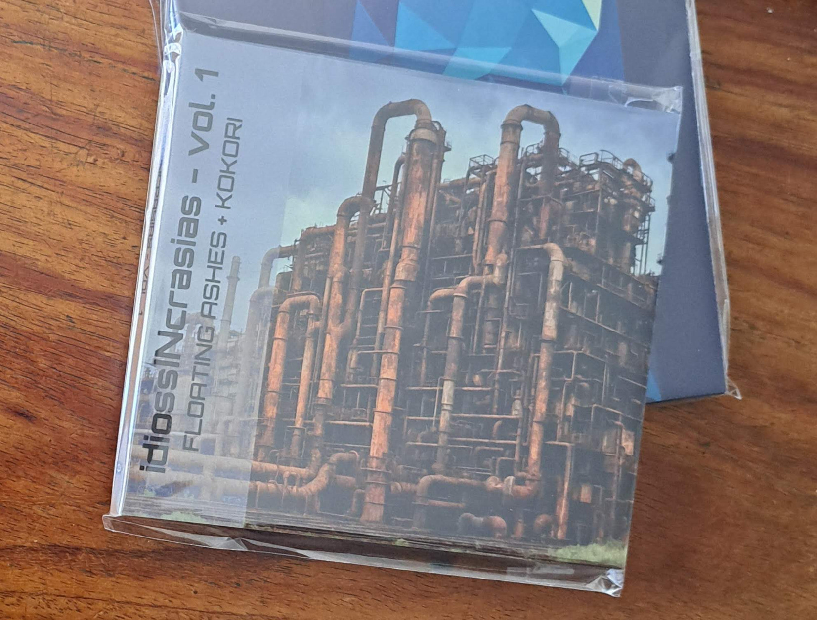 kokori&rsquo;s upcoming album (&ldquo;idiossINcrasias - Vol. 1&rdquo;, by Floating Ashes + kokori) on a sleeve protected CD, over another sleeve protected CD, kokori&rsquo;s previous album &ldquo;Rootkit&rdquo;.