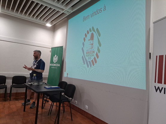 Uma pessoa a apresentar o evento, de pé numa sala