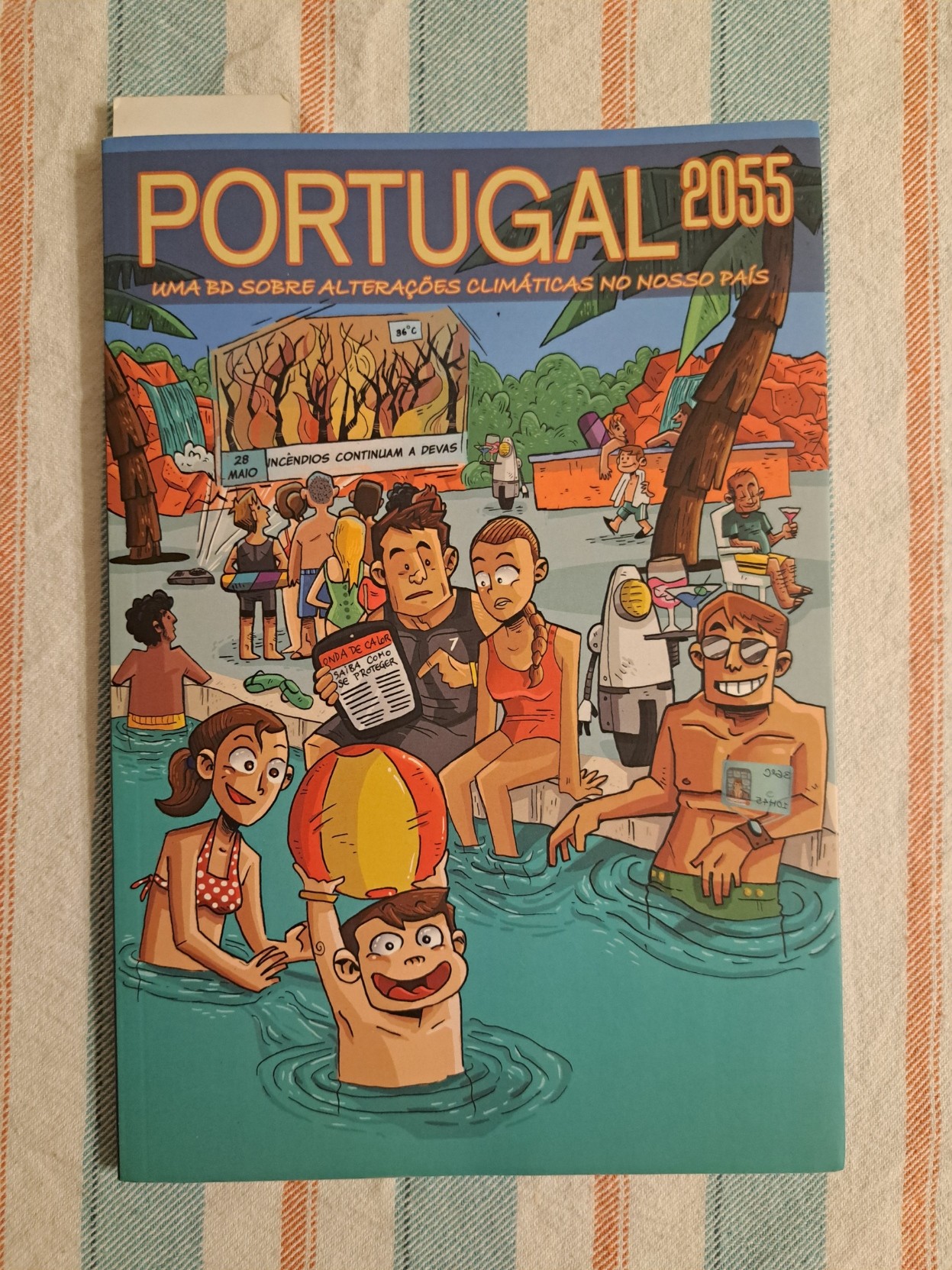Foto do livro de banda desenhada "Portugal 2025 - uma BD sobre alterações climáticas no nosso país". Estão 36º a 28 de maio, vem alí uma onda de calor e os incêndios já lavram, mas também há pessoas na piscina a divertir-se (e projectores holográficos, e robots a servir bebidas, e outras modernices).