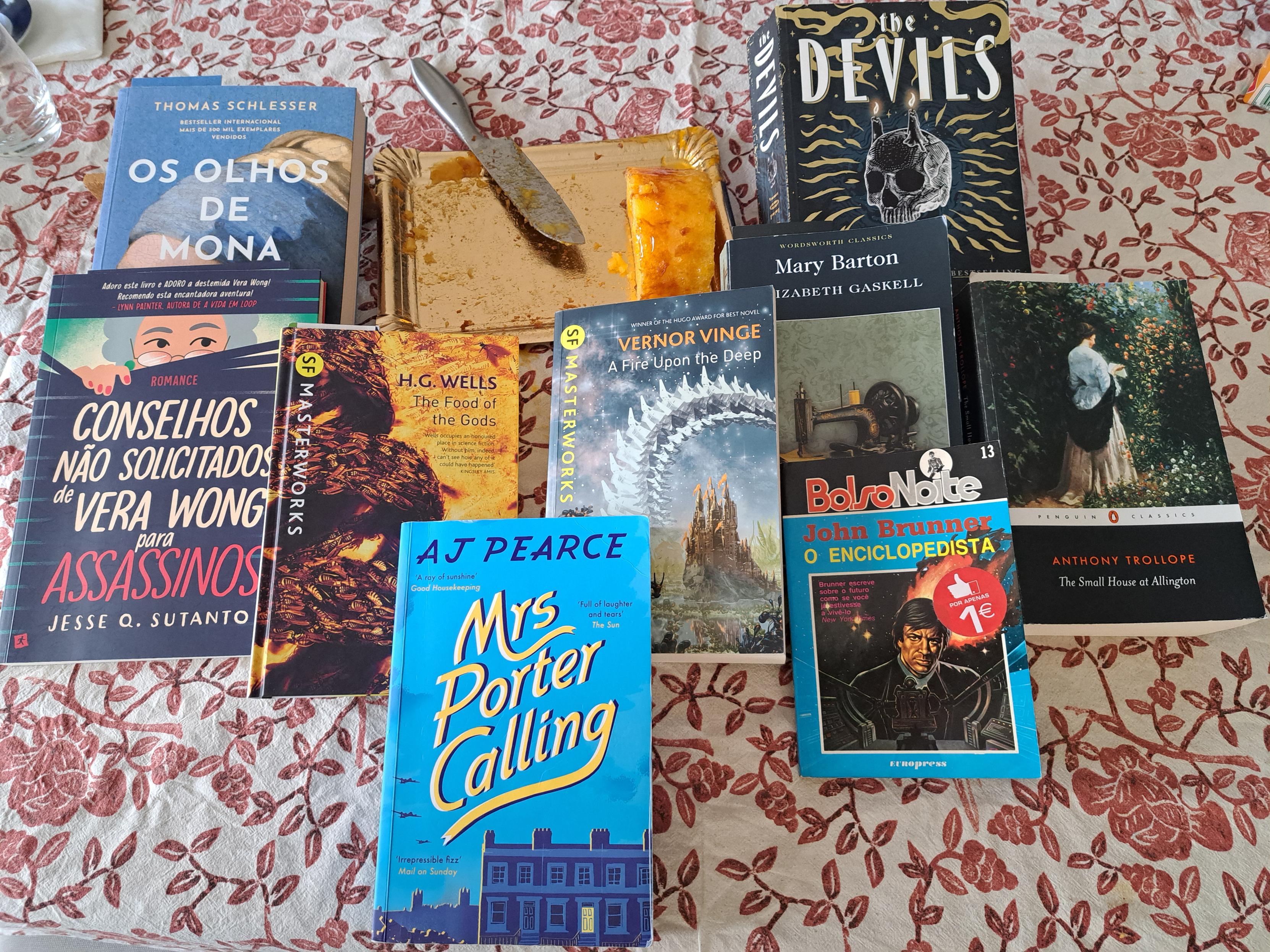 There's no crime but there's a knife, near the dessert it was used to cut. Surrounding it, nine books: 1) Os Olhos de Mona 2) Conselhos não solicitados de Vera Wong para Assassinos 3) The Food of God's 4) Mrs Porter Calling 5) A Fire Upon the Deep 6) The Devils 7) Mary Barton 8) O Enciclopedista 9) The Small House at Allington