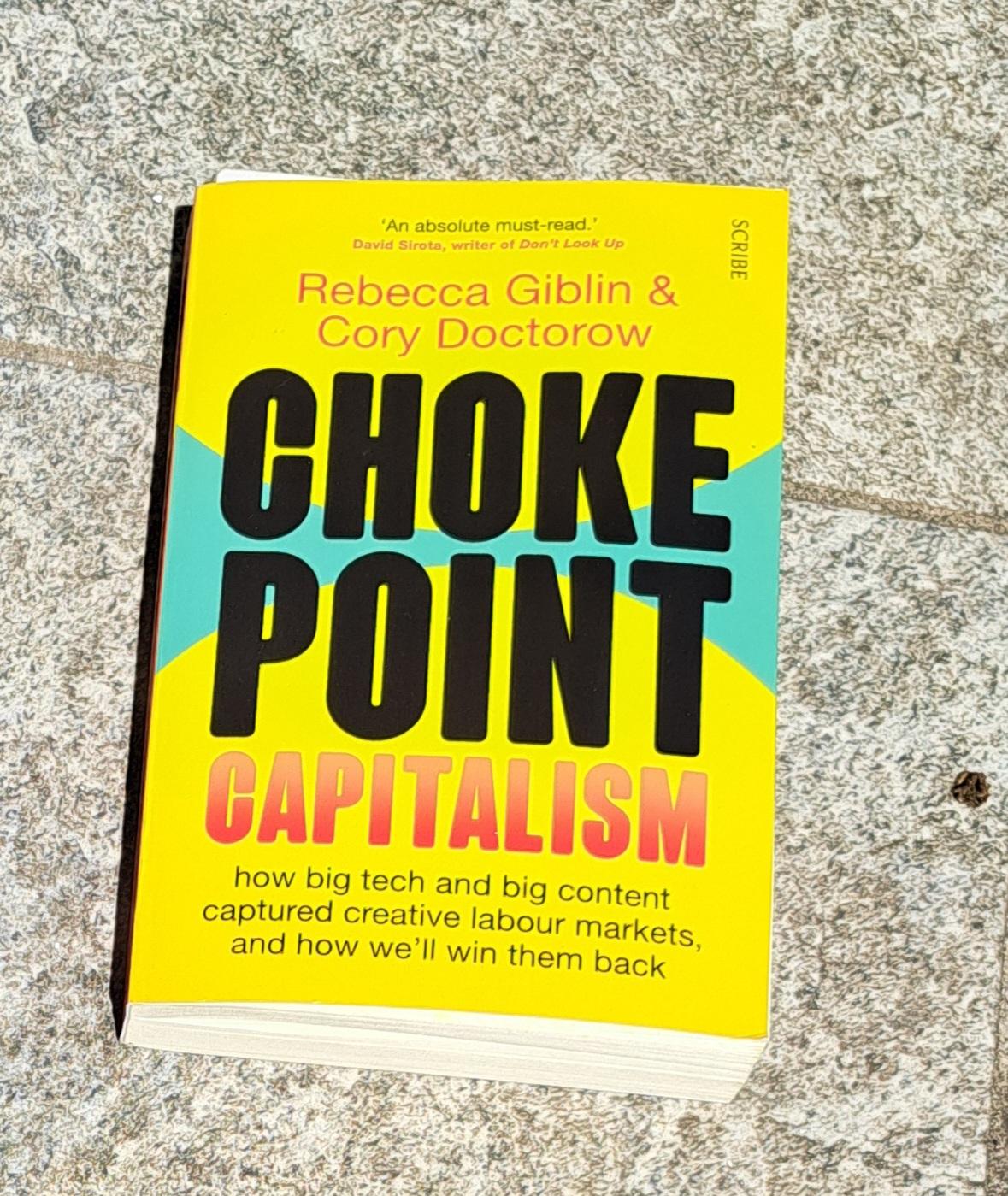 A paperback edition of an yellow cover book, "Chokepoint Capitalism", by Rebecca Giblin & Cory Doctorow, published by Scribe. It is about "how big tech and big content captured creative labour markets, and how we'll win them back". According to David Sirota, writer of Don't Look Up, it is 'An absolute must-read.'